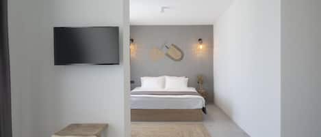 Un dormitorio moderno con una cama, un televisor y un taburete de madera.