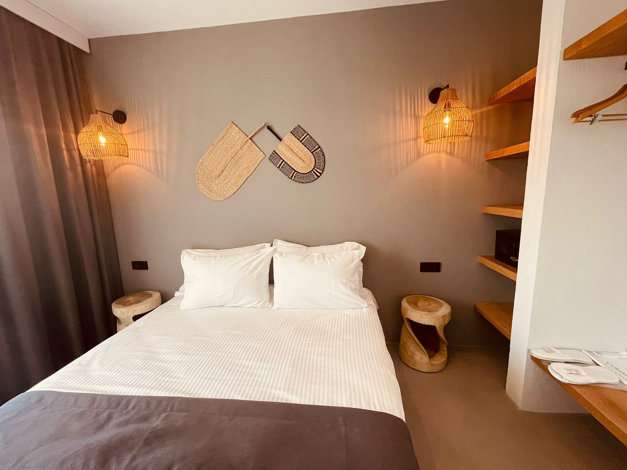 Un dormitorio moderno con una cama grande, dos lámparas fijadas a la pared, una mesita de noche de madera y un estante empotrado.