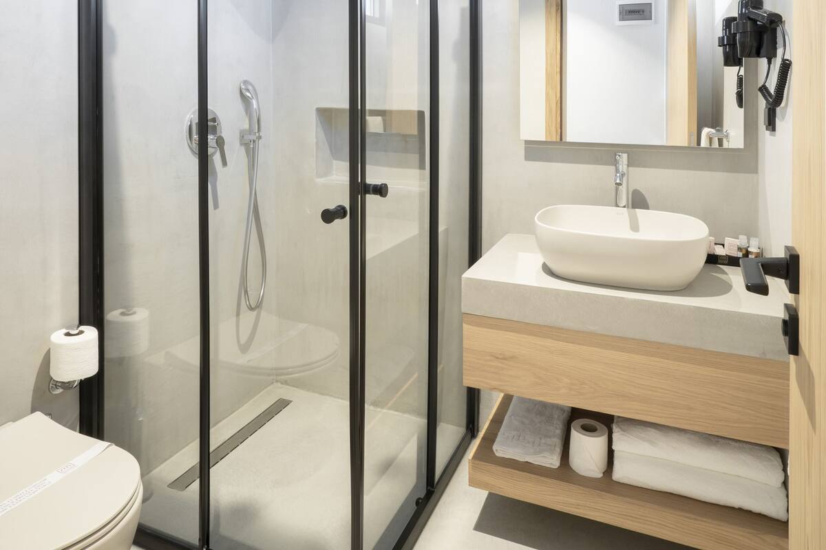 A modern bathroom with a glass-enclosed shower, a sink with a mirror above, and a toilet.