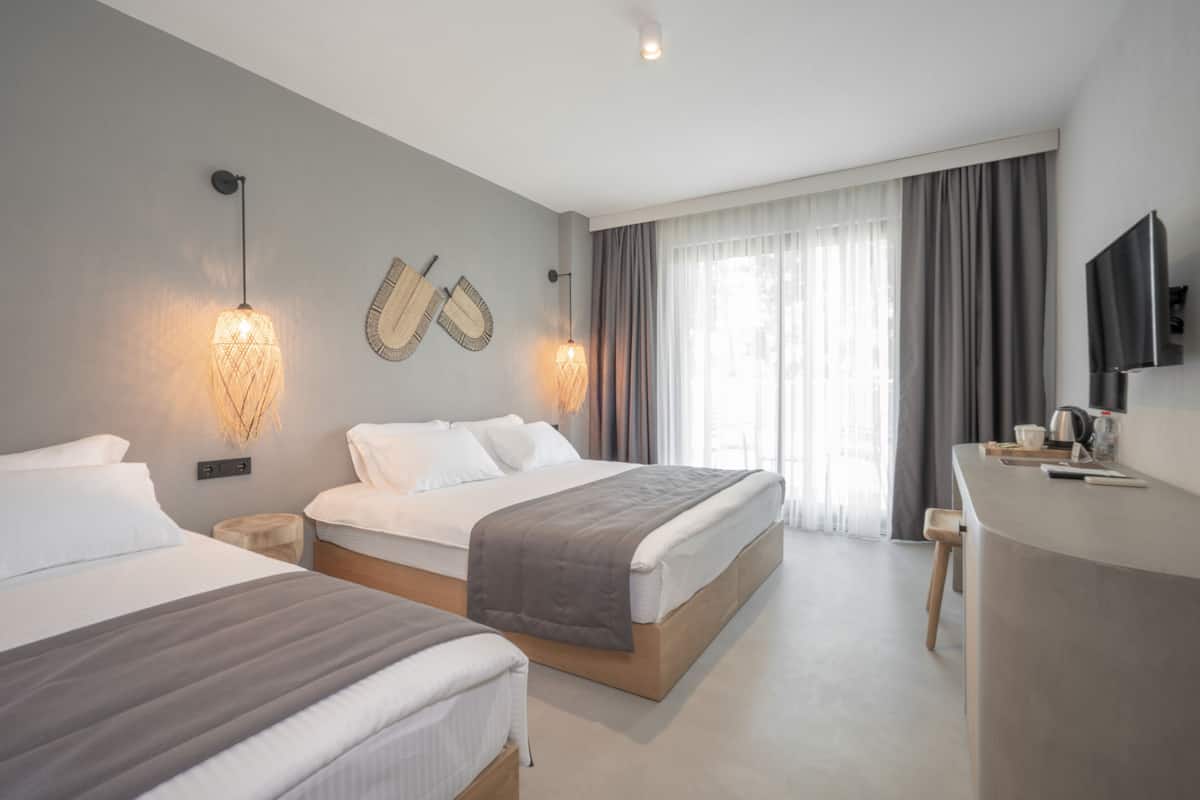 A modern hotel room with two beds, a desk, and a TV.