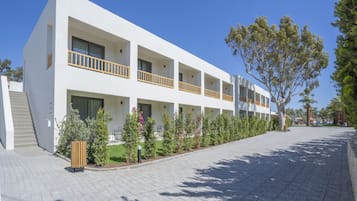 Un hôtel moderne à plusieurs étages, doté d’une façade blanche, de balcons et d’une allée pavée.