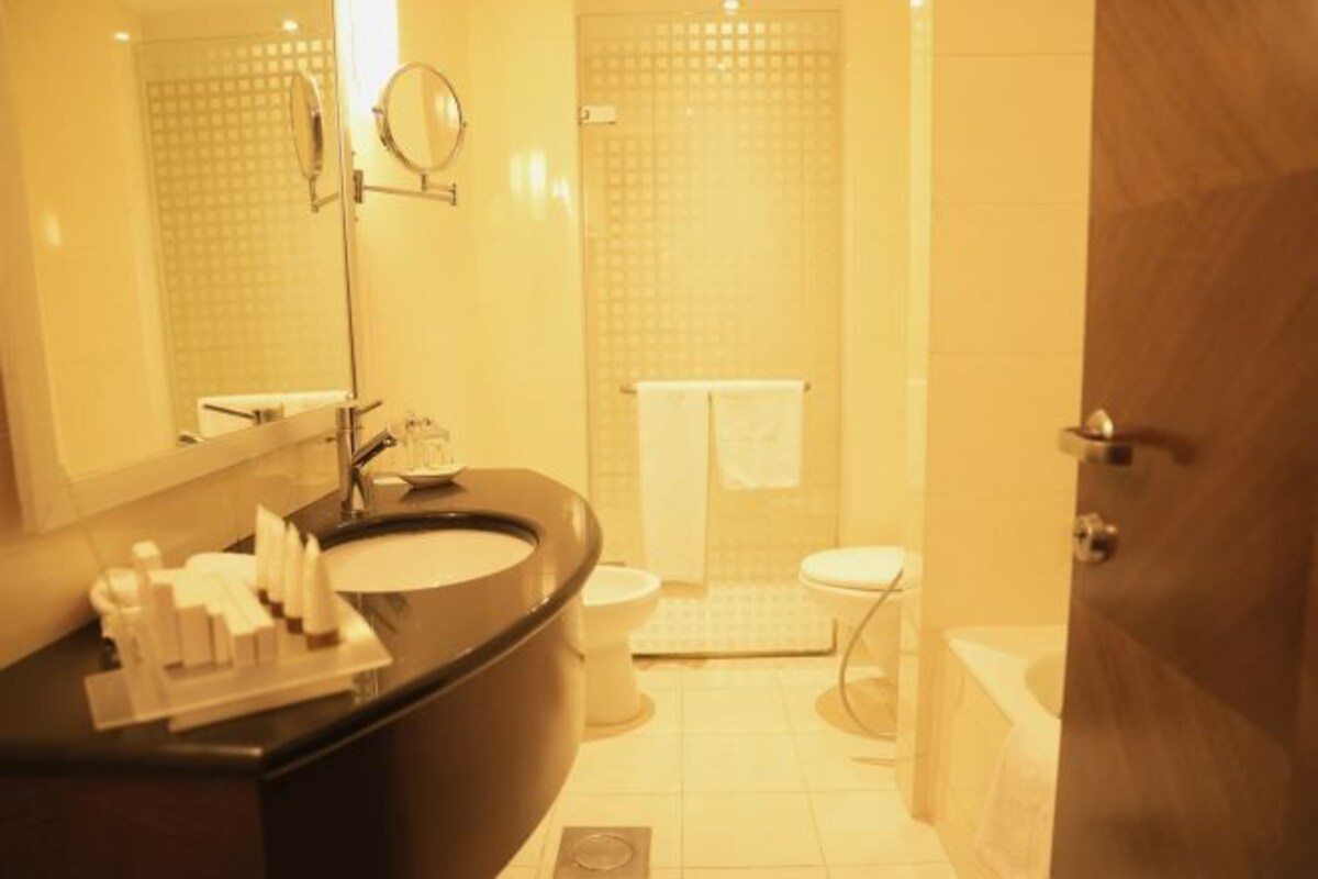 A bathroom with a black sink, a mirror, a toilet, and a shower area.