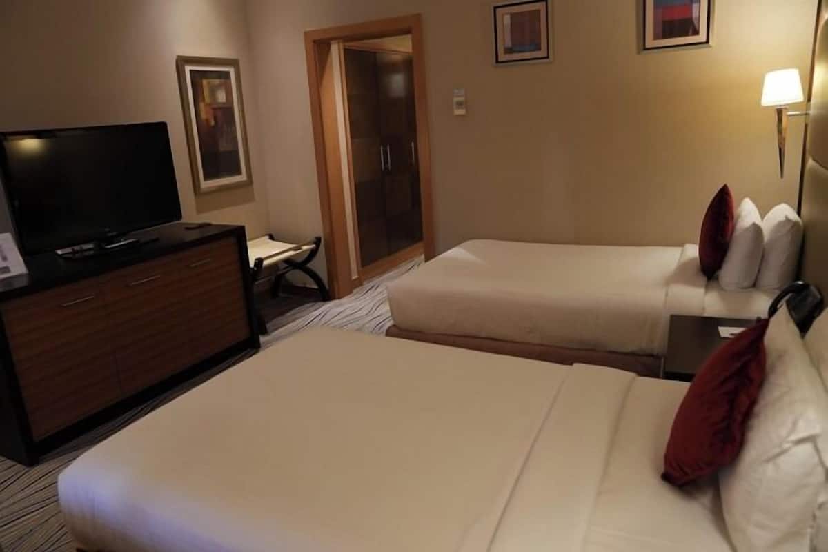 Una habitación de hotel con dos camas, televisión, escritorio y armario.