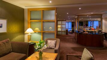 Un hall de hotel con zona de estar, una recepción y vistas al comedor.