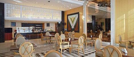 Un vestíbulo de hotel con una zona de bar, espacios para sentarse y una pared decorativa.