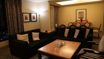 A living room with a sofa, a coffee table, and a dining area with a table and chairs.