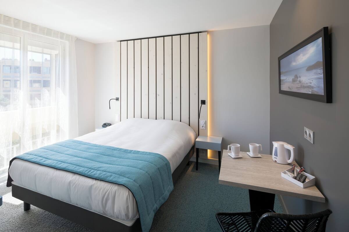 Une chambre d’hôtel moderne avec un grand lit, une table de chevet et une vue sur la ville.