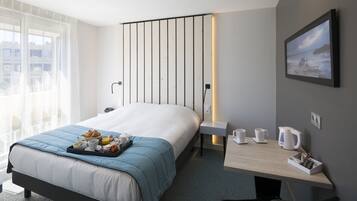 Una habitación de hotel con cama, mesita de noche y escritorio con silla.