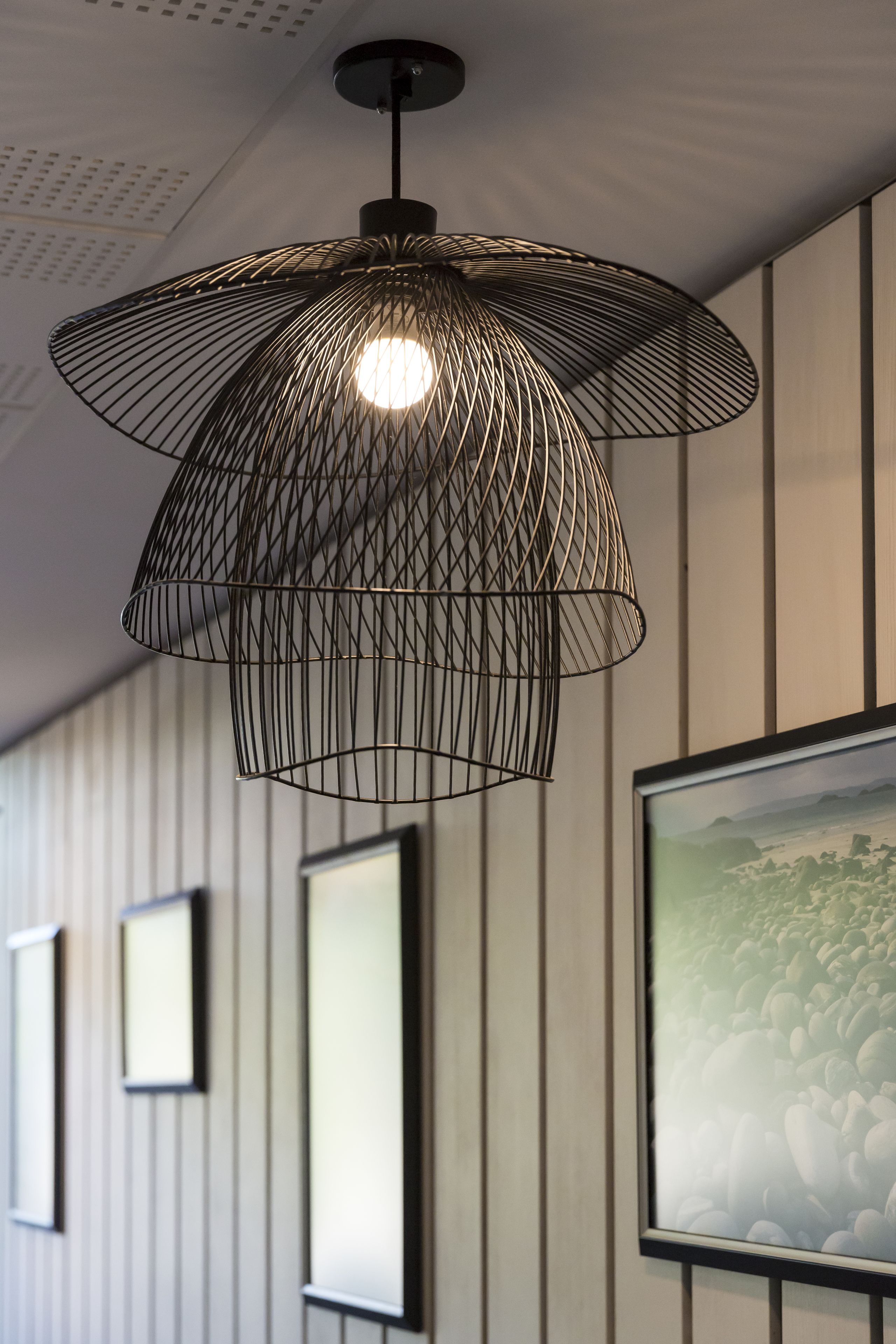 Een moderne pendelarmatuur met een geometrisch draadontwerp.