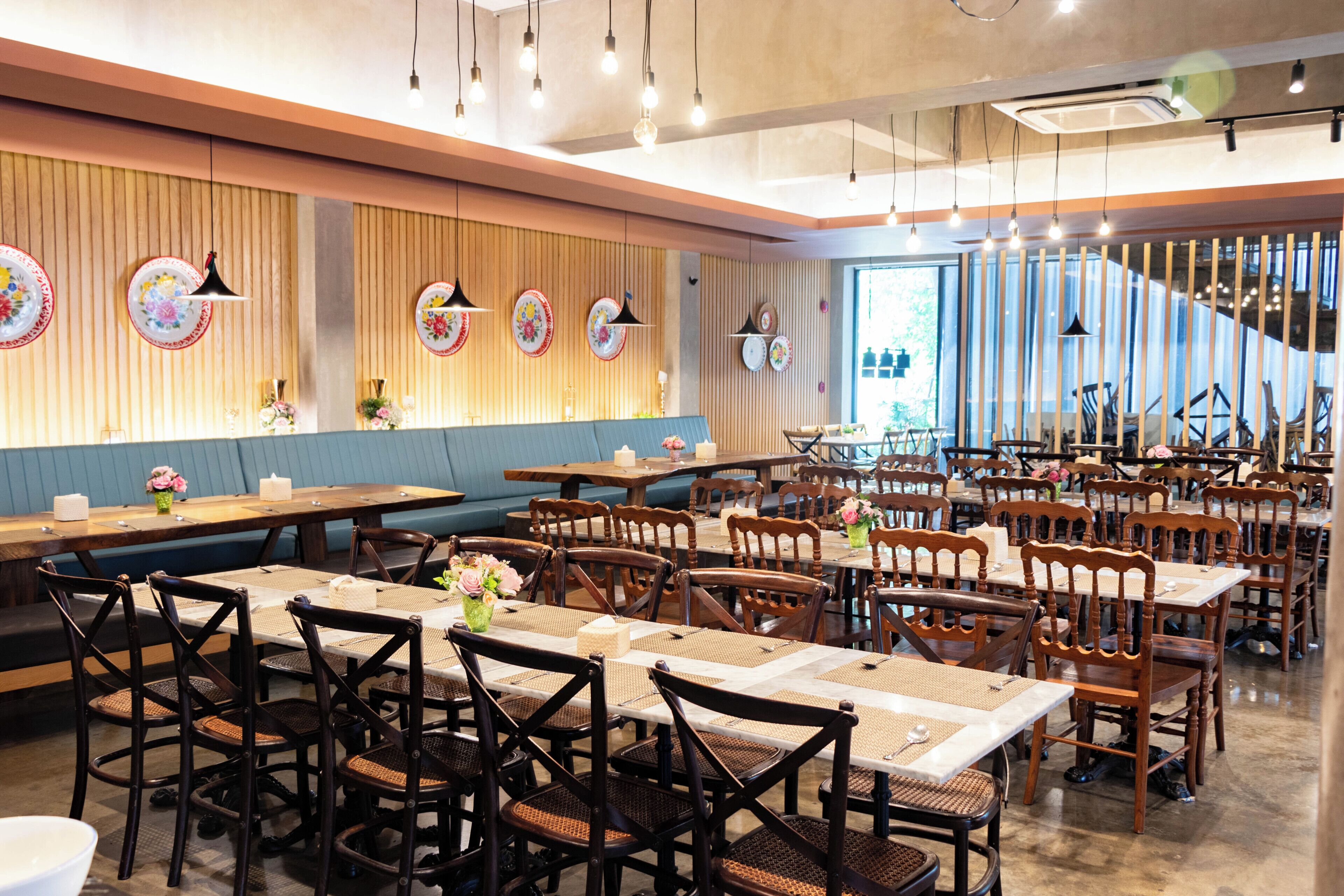 Een restaurant met meerdere eettafels en stoelen, houten paneelwanden en hangende吊り下げ灯.
