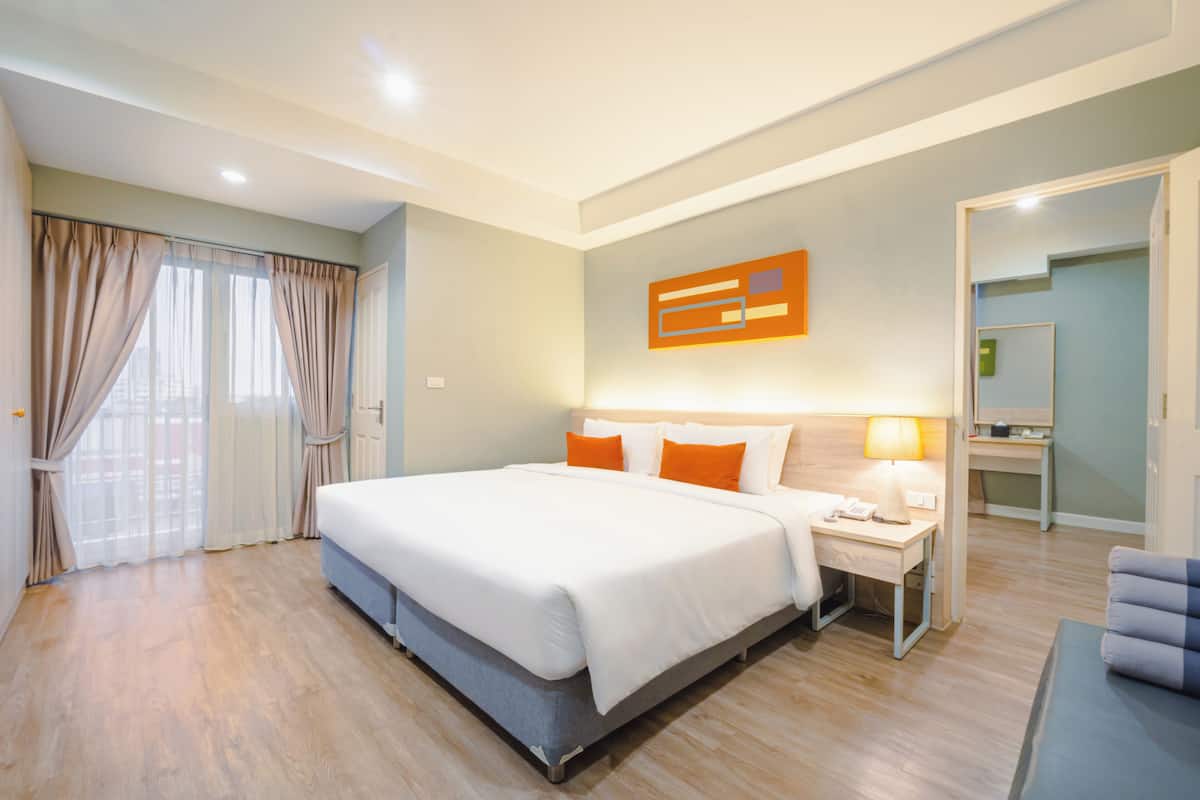 Une chambre d’hôtel avec un grand lit, un bureau avec une lampe et un miroir.