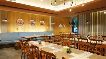 Un restaurante con mesas y sillas de madera, un banco tapizado de azul y platos decorativos en la pared.