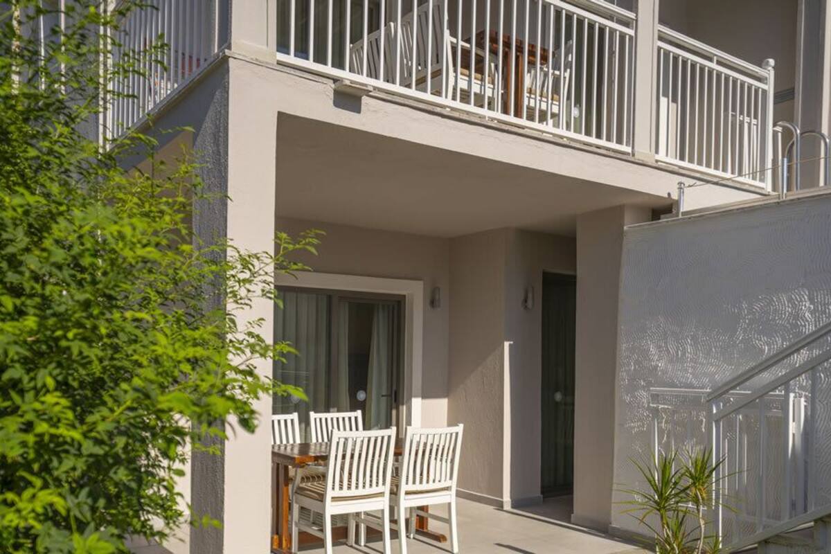 Een modern gebouw met balkon, een deur en een kleine tafel met stoelen.