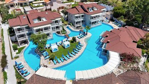 Ett semesterhotell med en stor pool, flera balkonger och solstolar.