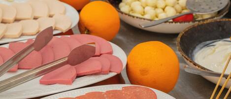 Una mesa de buffet con diversos alimentos, entre ellos, carnes cortadas, frutas y verduras.