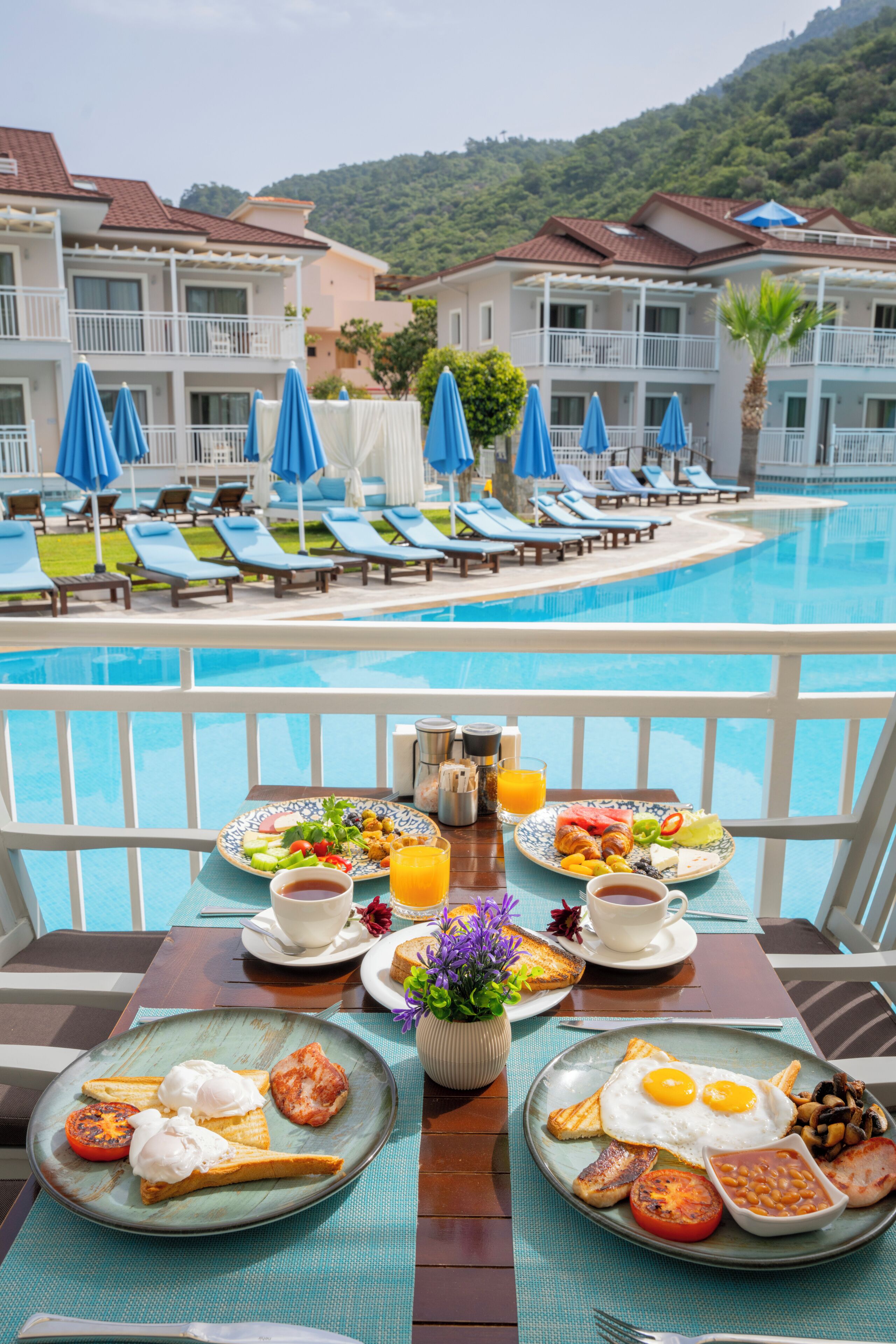 A poolside breakfast setup with a view of a hotel and pool.