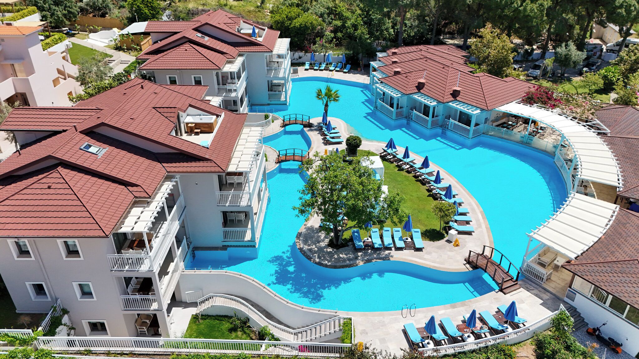 A resort with a large central pool, multiple balconies, and a well-maintained lawn area.