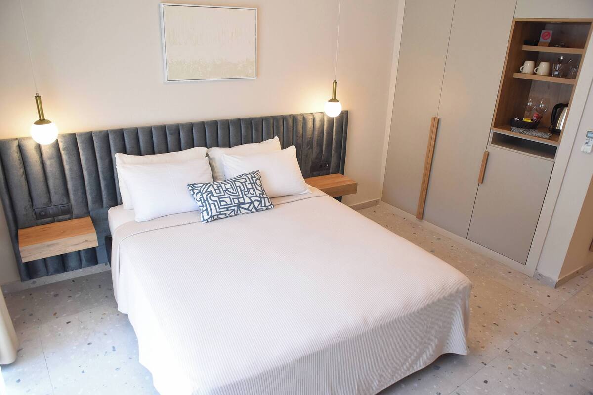 Een netjes ingerichte slaapkamer met een bed, nachtkastjes, een kledingkast en wandlampen.