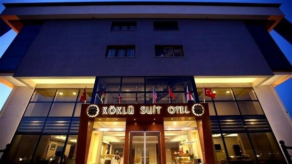 The exterior of Köklu Suit Hotel with a modern facade and multiple flags displayed outside. - Koklu Suit Otel (Honaz)