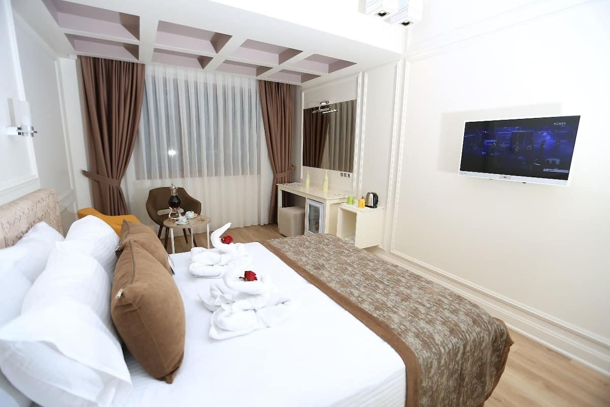 A hotel room with a bed, a desk, a TV, and a bathroom visible through an open door.