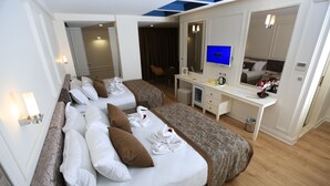Hotellihuone, jossa on kaksi sänkyä, työpöytä, peili ja televisio.