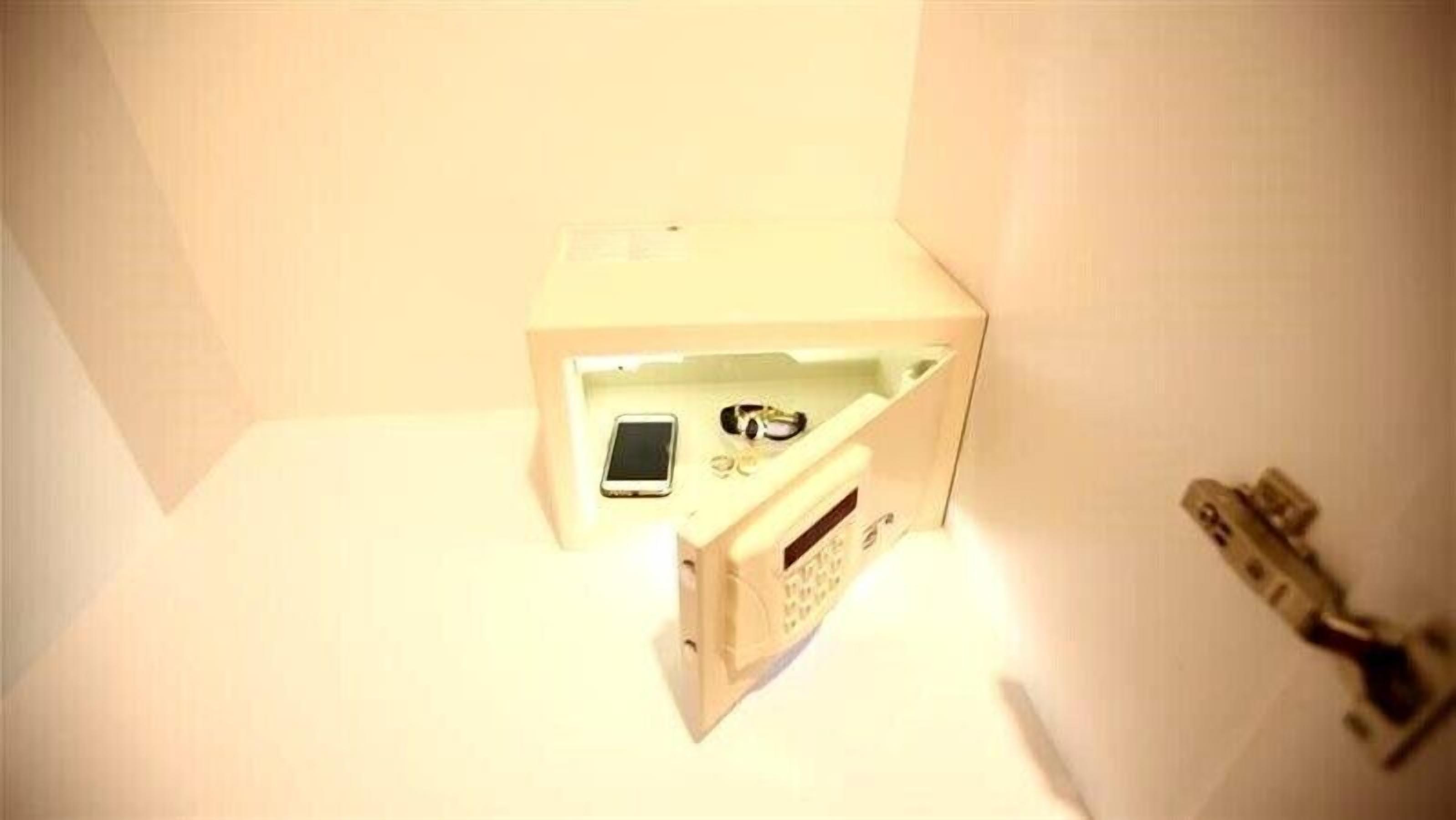 A small, enclosed space with a white interior, a mobile phone, and a small electronic device on a surface.