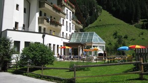 A multi-story building with balconies, outdoor seating, and a mountain backdrop. - Hotel Tia Monte (Kaunertal)