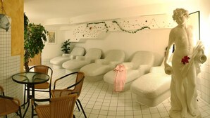 A living room with a sofa set, a statue, a dining table with chairs, and a potted plant. - Hotel Tia Monte (Kaunertal)
