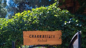 Un letrero de madera con la inscripción 'Chakrabeach Kabak', que indica el camino hacia una escalera de piedra.