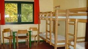 Una habitación con literas, una mesita y sillas.