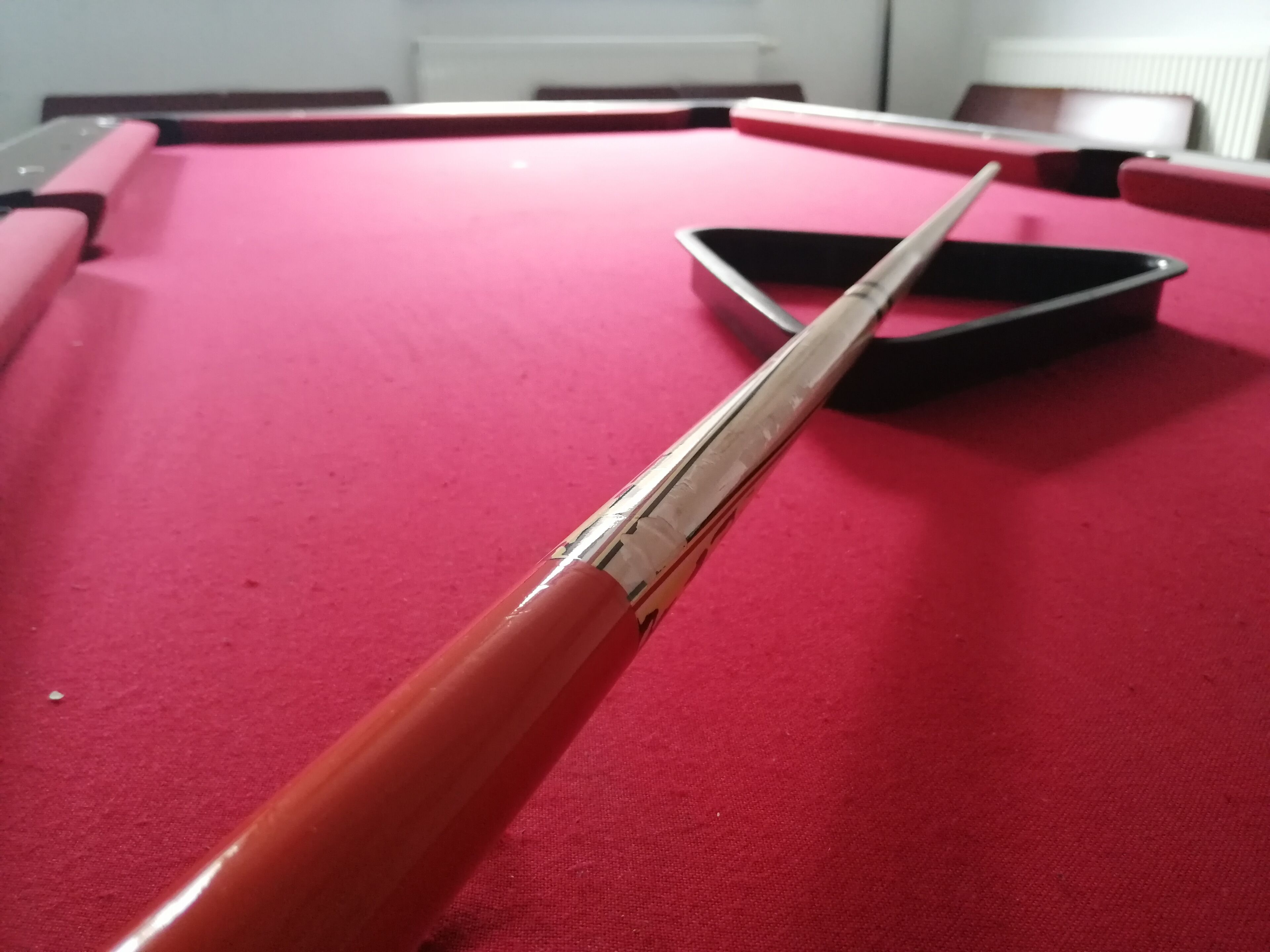 Een close-up van een biljarthockeystick punt met een rode vilten ondergrond.