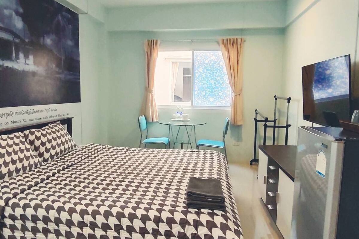 Ein Hotelzimmer mit Bett, Schreibtisch, Stuhl, Fernseher und einem Fenster mit Vorhängen.