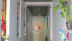 A hallway with a green ceiling, a white door at the end, and various plants and decorations along the walls. - Machima House (Phuket)