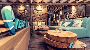 A cozy interior with a stone wall, wooden furniture, and a blue sofa with patterned cushions. - Keros Blue (Lemnos)