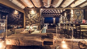 A cozy, rustic interior with stone walls, wooden furniture, and a bar area. - Keros Blue (Lemnos)