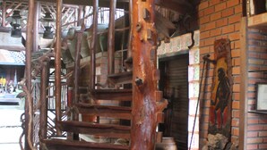A rustic interior with a wooden spiral staircase, brick walls, and a rustic decor including pottery and a wooden sculpture. - Khaochan Resort (Pak Phayun)