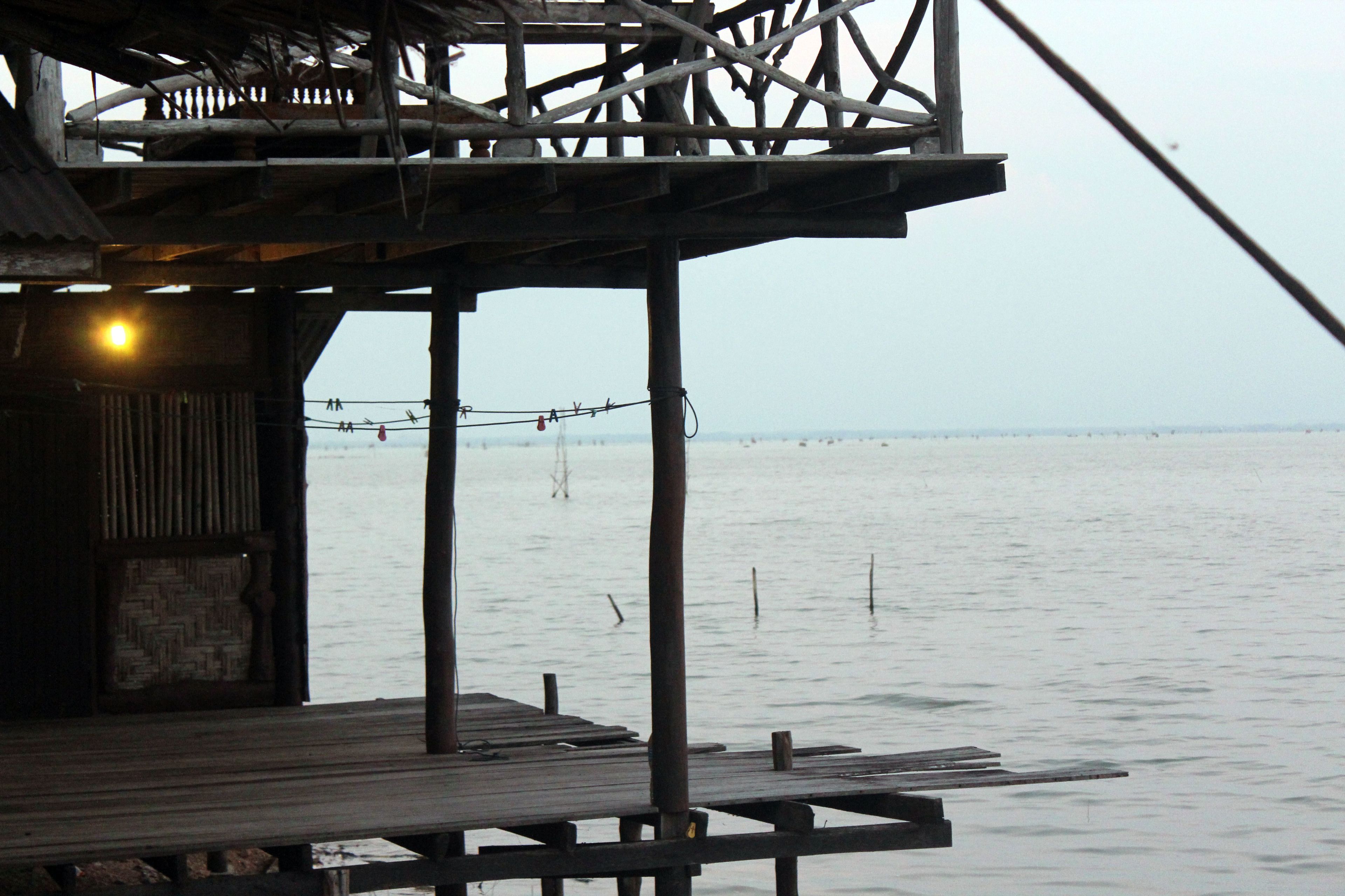 A wooden pier extending over calm water, with a simple structure at the end.