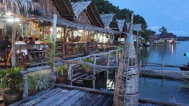 A wooden dock with thatched roofs, potted plants, and a calm water body. - Khaochan Resort (Pak Phayun)