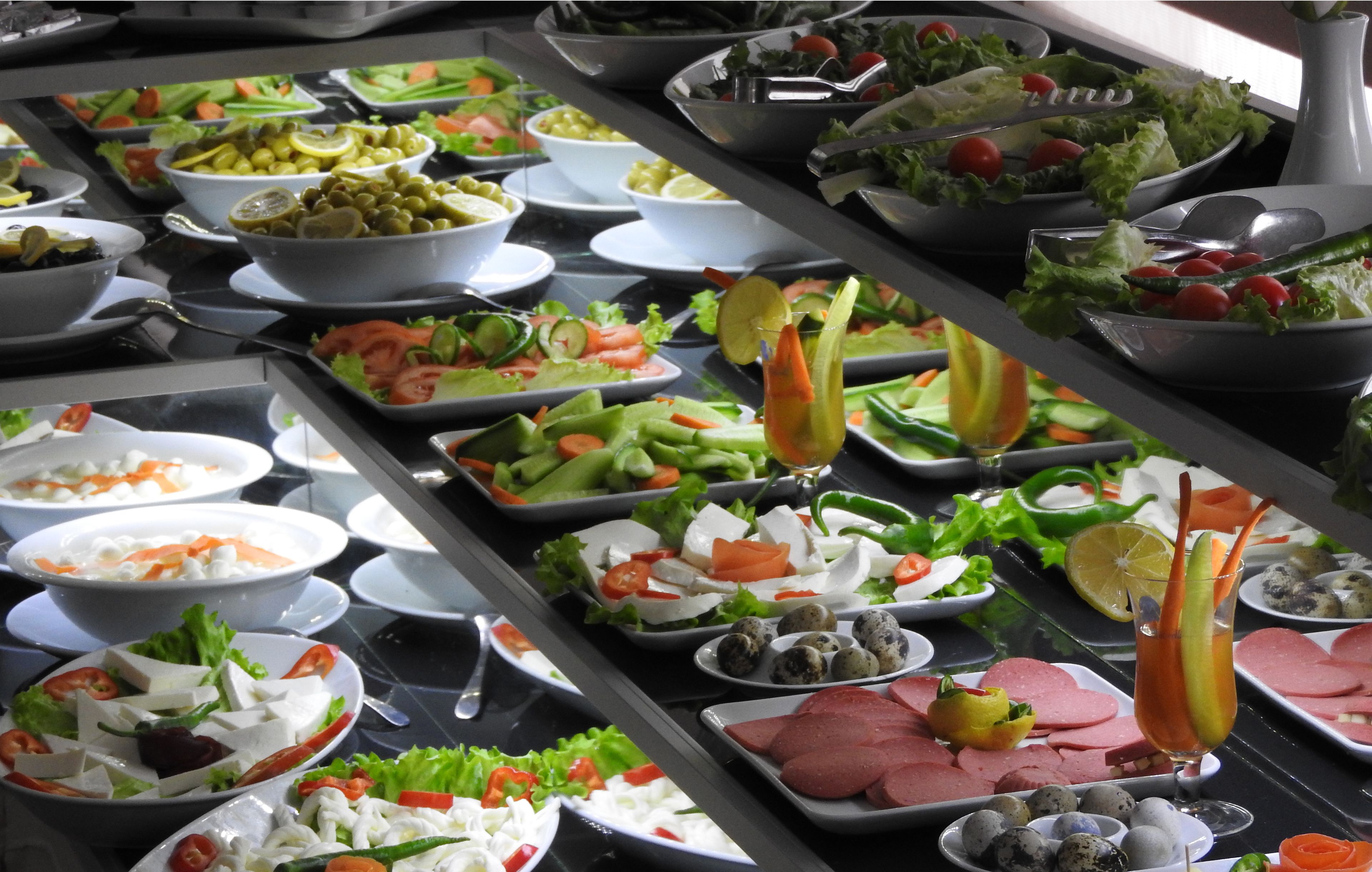 A buffet with various dishes including salads, meats, and seafood.