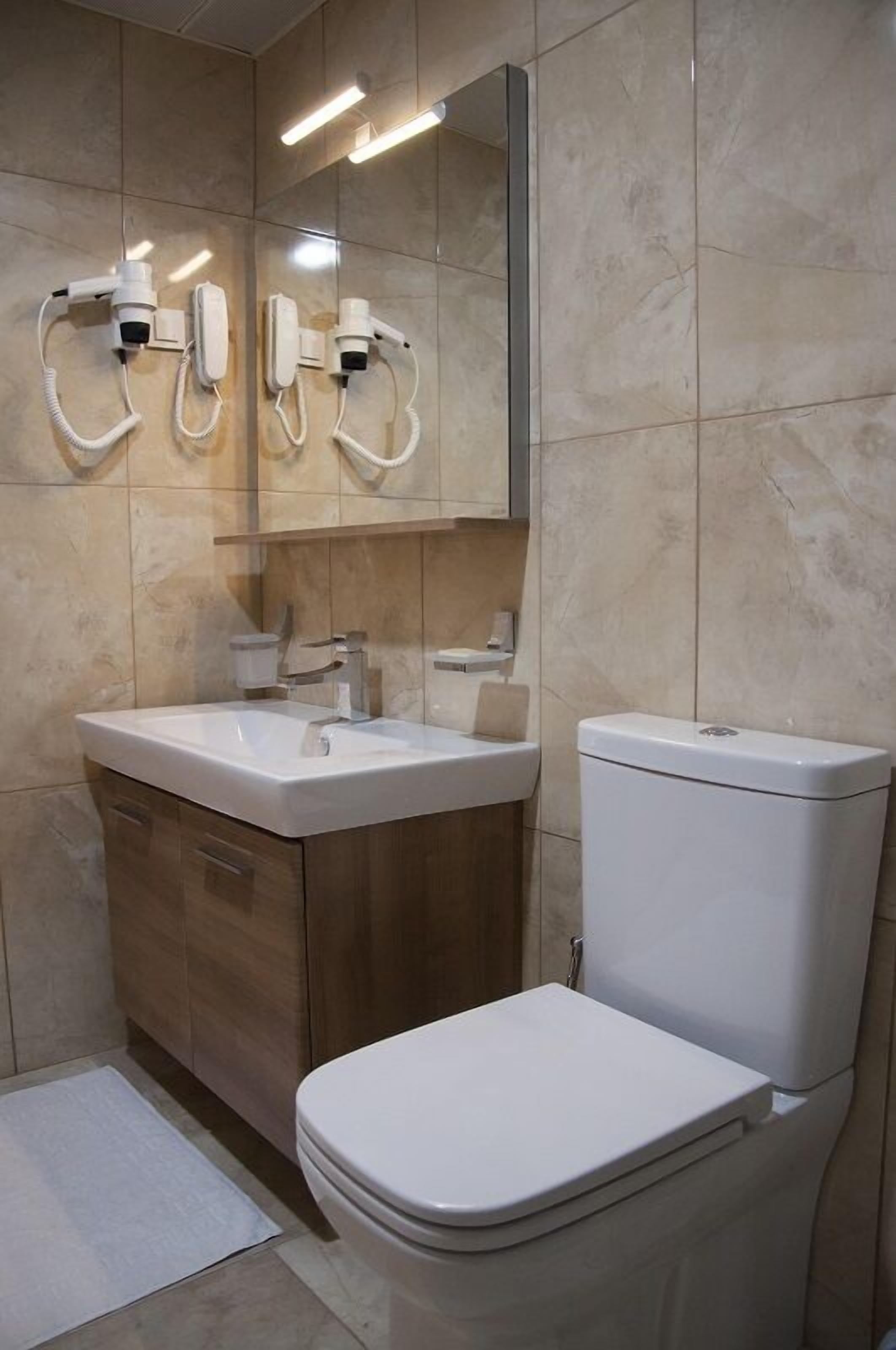 A modern bathroom with a white sink, wooden vanity, and a toilet.