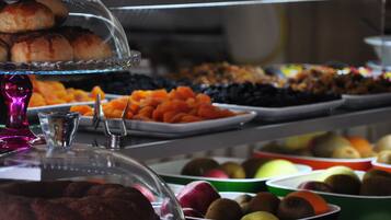 Un buffet proposant une variété de plats, notamment des pâtisseries, des fruits et des légumes.