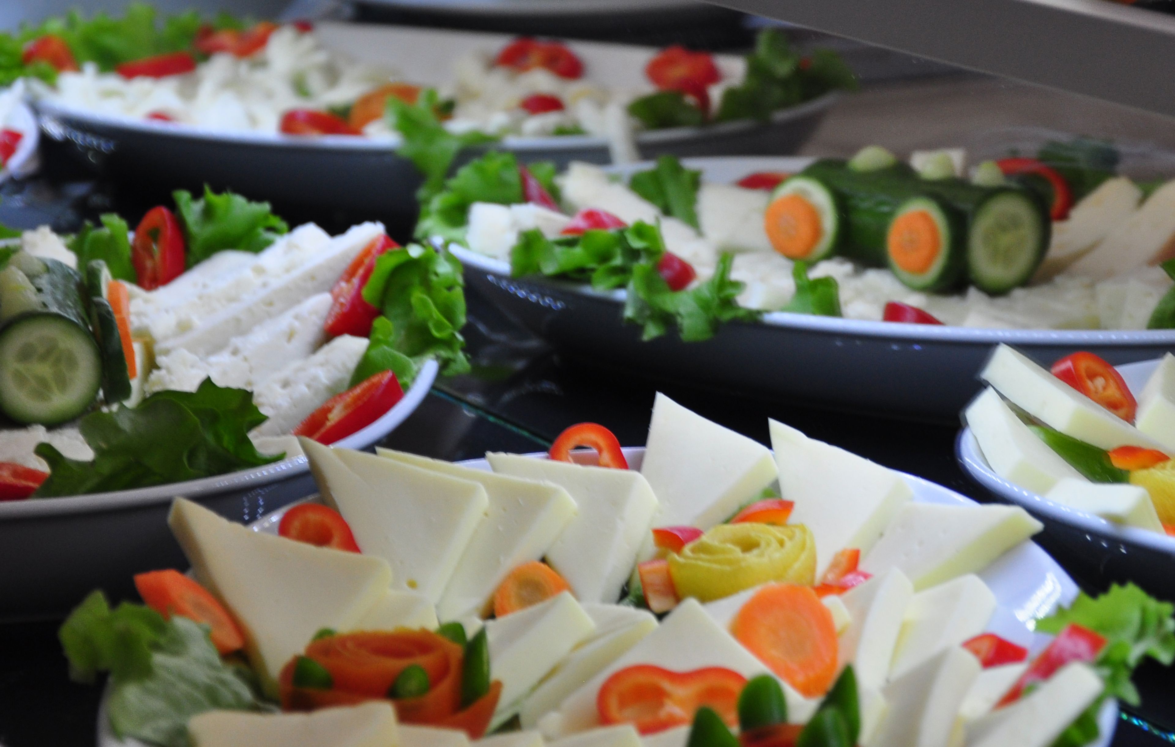A buffet with various dishes including sliced vegetables and cheese.