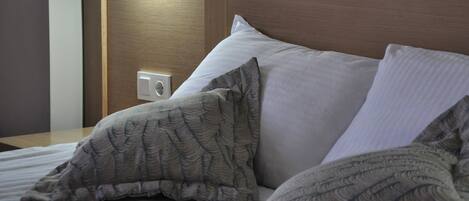 A hotel room with a bed, pillows, and a nightstand.