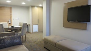 Ein Hotelzimmer mit einer Couch, einem an der Wand montierten Fernseher, einem kleinen Tisch und einem Schrank.