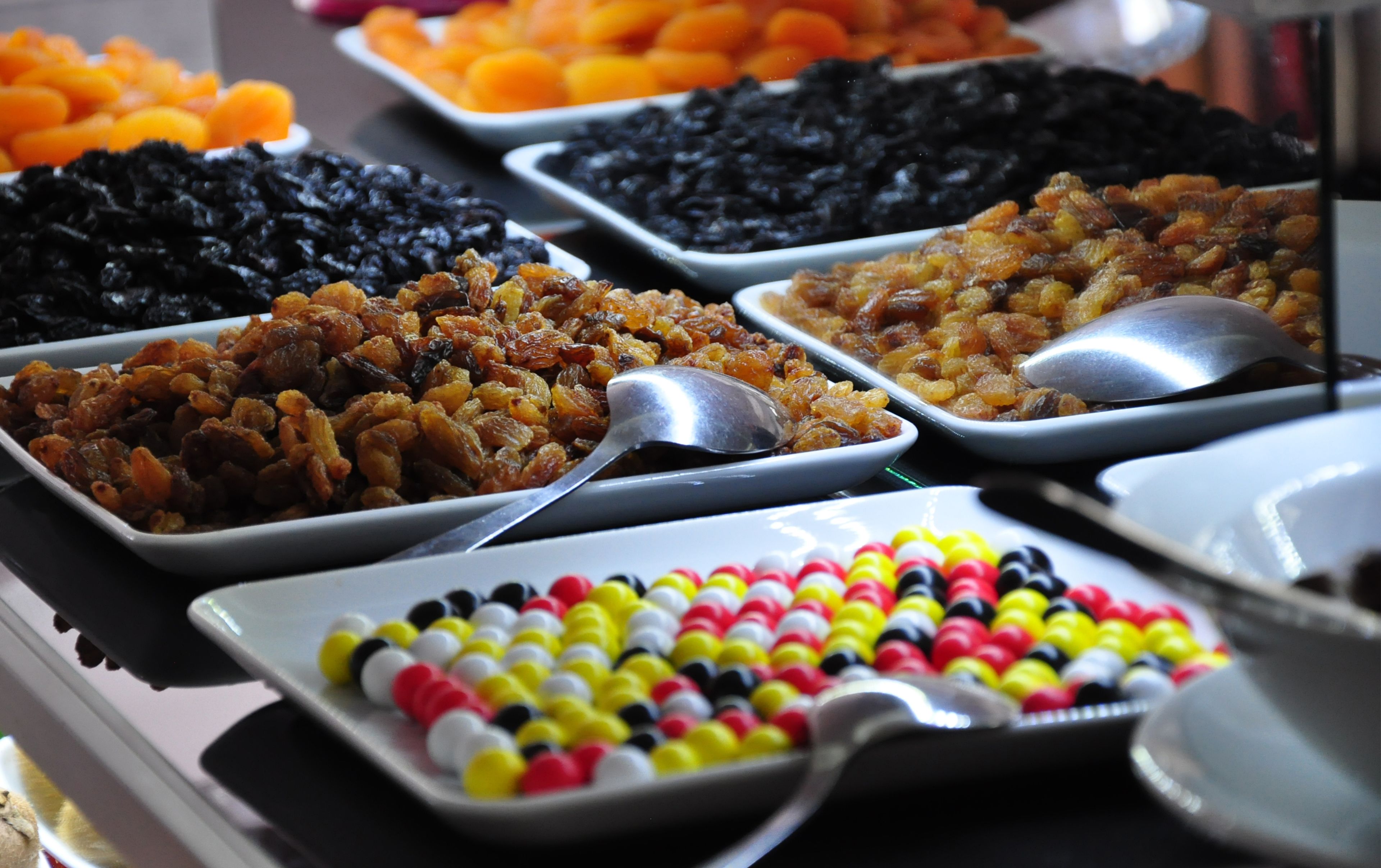 Un buffet proposant une variété de plats, notamment du riz noir, des fruits aux couleurs vives et des bonbons multicolores.