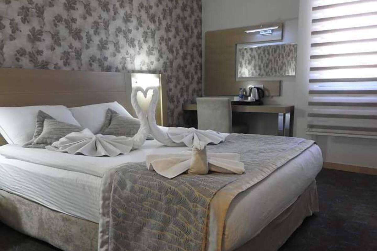 A neatly made bed with pillows, a bedside table with a lamp, and a chair.