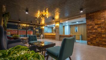 A modern lobby with a reception desk, seating area, and large windows.