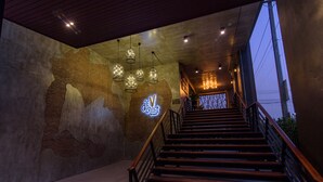 Una escalera con escalones de madera y barandillas metálicas que conduce a una plataforma con un letrero de neón y luces colgantes.