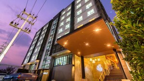 Un hotel moderno con varios pisos, amplias ventanas y una entrada bien iluminada.