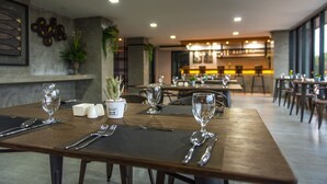 Un comedor con mesas dispuestas para dos, con un diseño moderno y una paleta de colores neutros.